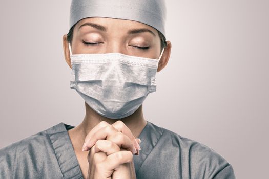 COVID-19 Coronavirus outbreak Doctor praying for help. Young woman medical nurse portrait hoping for positive future.