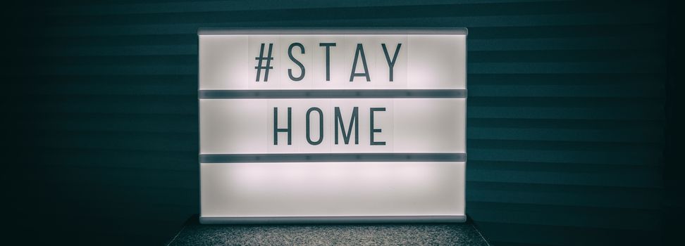 COVID-19 banner Coronavirus staying at home lightbox message sign with text, hashtag STAYHOME glowing in light to promote self isolation staying at home header background.