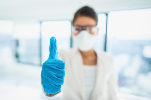 Coronavirus success happy news lab researcher doing thumbs up with medical gloves for vaccine. PPE for COVID-19 healthcare.
