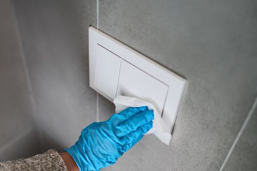 Surface sanitizing wipes of home surfaces, wall button switches wiping paper towel sanitizer with gloves.