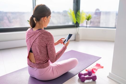 Exercise staying home woman watching fitness videos online on mobile phone yoga workout live streaming influencer fit girl, working out in living room of apartment house.