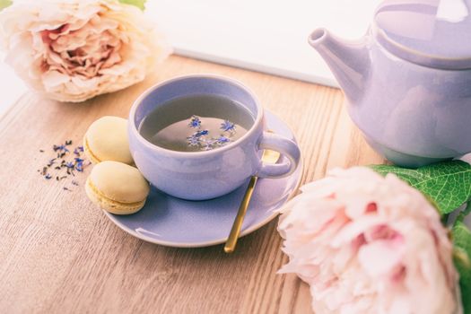 Tea cup home serving for one english black tea black tea with teapot and macarons cookies with lovely pink peonies flowers decoration.