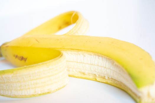 A Whole banana with the skin peeled back against a plain white background