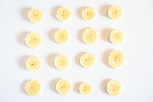 Slices of banana in a square pattern against a plain white background