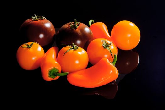 Tomatoes and peppers on a black surface