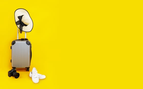 Travel bag, Luggage, Straw hat, digital camera, shoes and sunglasses on yellow background with copy space banner. suitcase, hat with black ribbon, black sunglasses, camera, white sneakers isolated on yellow background. Summer  travel concept.