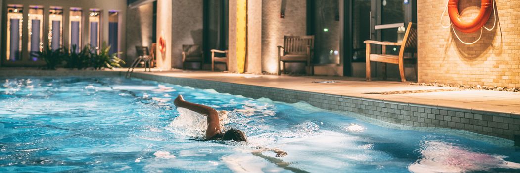 Swimming pool of condo buildings re-opening after COVID-19 confinement. Swimmer woman doing crawl in public pool banner panoramic.