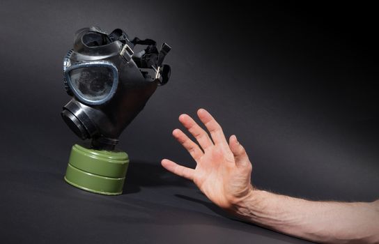 Man in room, trying to reach for vintage gasmask - Isolated on black - Green filter
