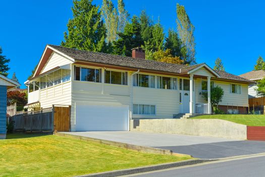 Expanded family house with wide garage, concrete driveway and mowed lawn on the front yard