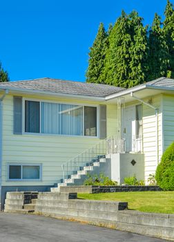 Entrance of family house with concrete doorsteps and asphalt driveway in front.