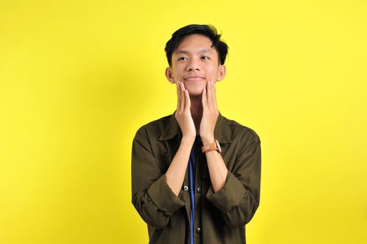 Happy of young Asian man smiling confident look at on top, isolated on yellow background