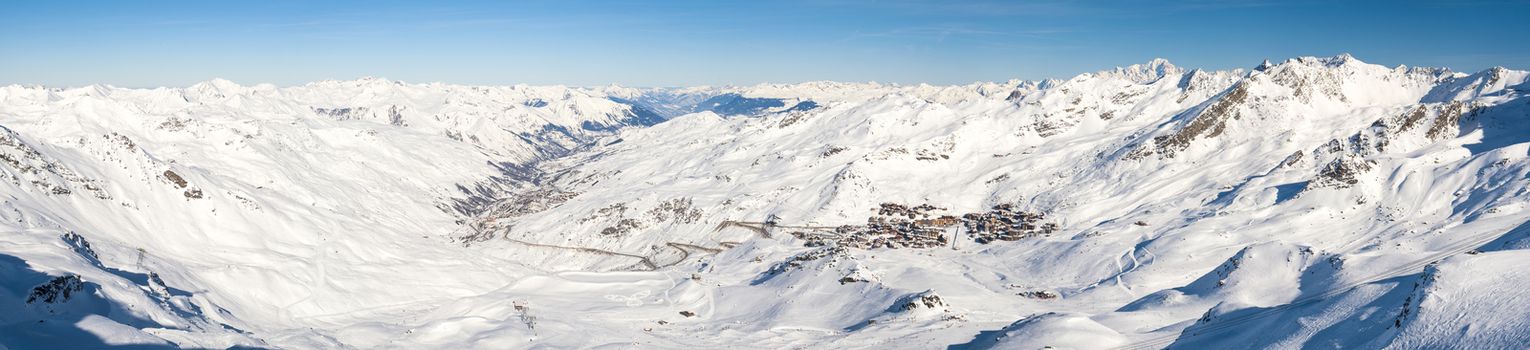 Panoramic view of a snow covered mountain range looking down valley with village ski resort