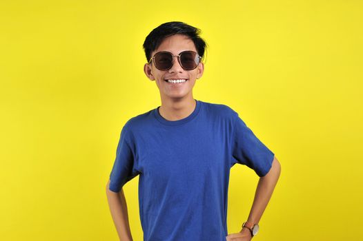 Happy Young Asian man smiling wearing glasses, isolated on yellow background
