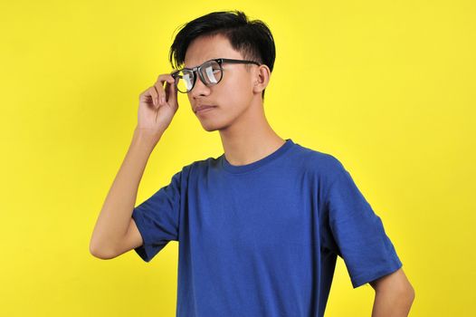 Portrait of gentle Asian man wearing glasses, isolated on yellow background