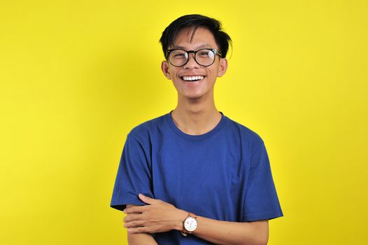 Happy Young Asian man smiling wearing glasses, isolated on yellow background