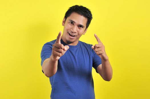 Young asian man happy and excited expressing winning gesture. Successful and celebrating on yellow background