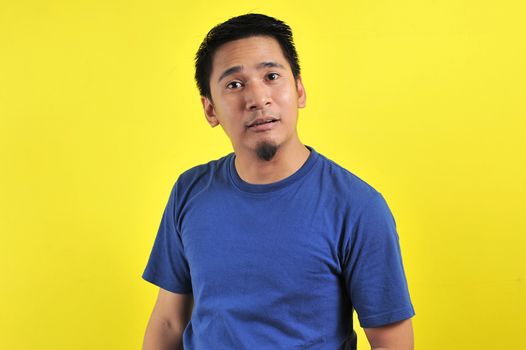 Young Asian man doing funny mouth gesture, isolated on yellow background