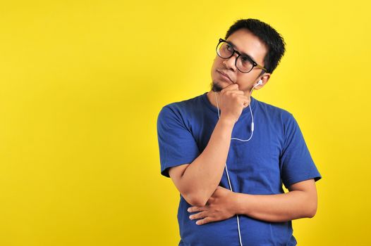 Man wear glasses, wondering or imagining ideas, daydreaming and looking up to copy space against orange wall