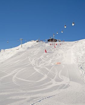 View from the bottom of a ski slope covered in snow with lifts