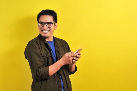 Portrait of happy smiling Asian man using smartphone wearing casual t-shirt and jacket with eyesglasses, get the best price, using simple mobile banking payment