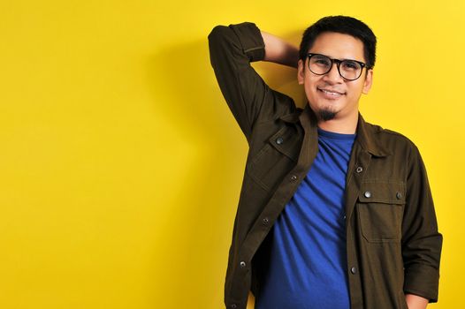 Portrait of a handsome man smile in blue t-shirt, jacket and eyesglasses, isolated on yellow background