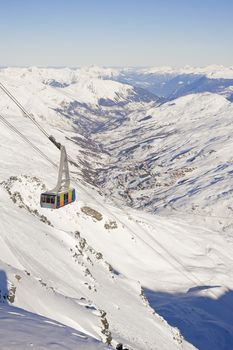 Large cable car ascending a snowy mountain valley