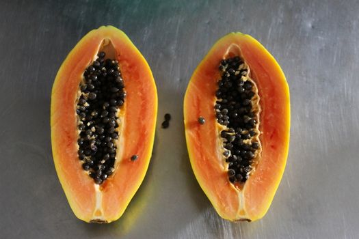 Two halves of papaya fruit on the kitchen table. Papaya fruit with black seeds.