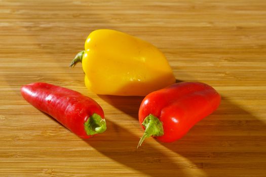 Small red and yellow peppers on a wooden background