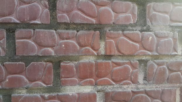 Closeup texture of red brick wall. A background of a weathered old exterior brick wall in the sunshine.