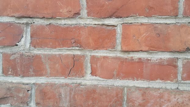 Closeup texture of red brick wall. A background of a weathered old exterior brick wall in the sunshine.