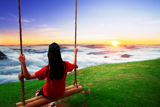 Female tourists sit and swing on the top of the high hill