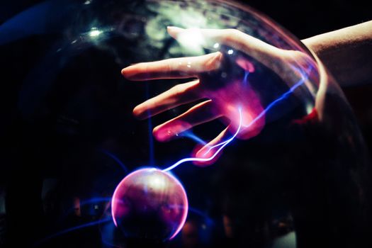 A plasma ball that is releasing electricity on the hand