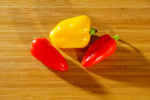 Small red and yellow peppers on a wooden background