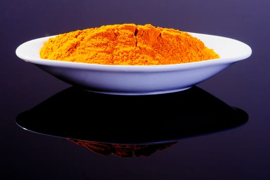 Turmeric in a white plate on black background