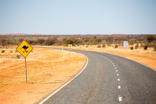 A defaced kangaroo warning road sign on the Lasseter Highway near Uluru in the Northern Territory, Australia