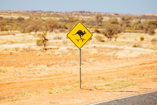 A defaced kangaroo warning road sign on the Lasseter Highway near Uluru in the Northern Territory, Australia