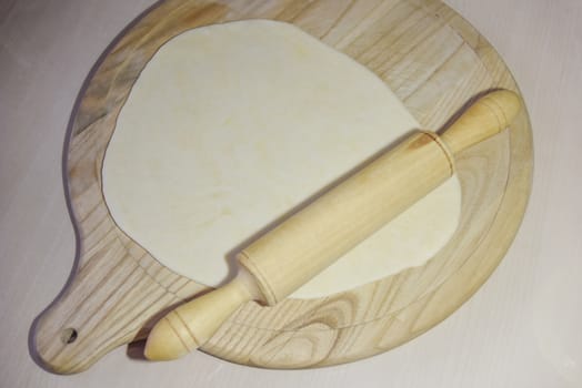 selective focus at the dough and roller at the wooden chopping board