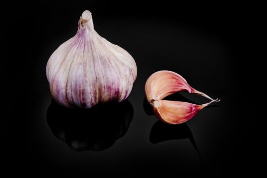 Close-up of garlic with reflection on black background.