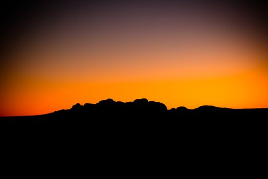 The silhouette of the boulders of the Olgas at sunset on a clear winter's evening in Northern Territory, Australia.