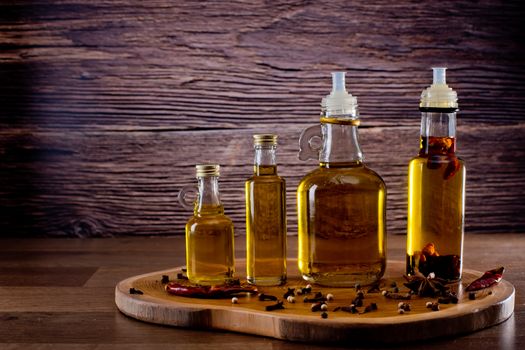 Bottles with olive oil with spices on a wooden background. Backgrounds for the kitchen.