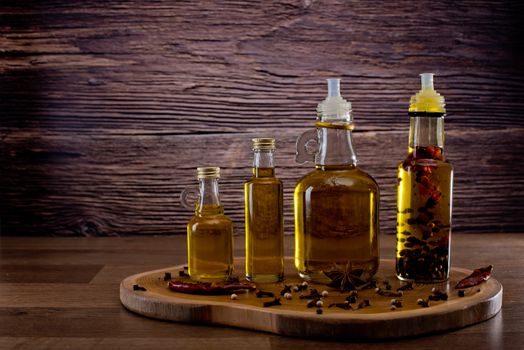 Bottles with olive oil with spices on a wooden background. Backgrounds for the kitchen.