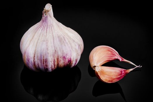 Close-up of garlic with reflection on black background.