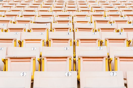 A lot of Light Orange Seat at football stadium in the morning.