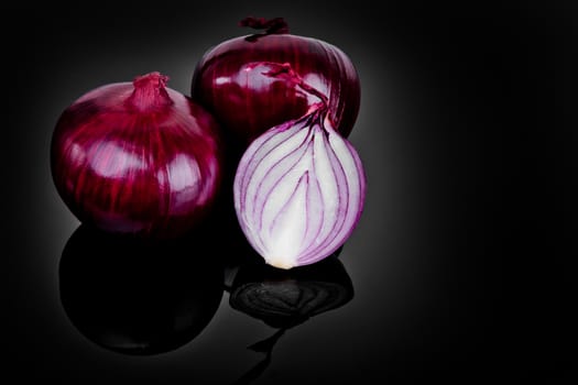 Red onion and half slice on black background with reflect.