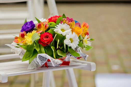 A beautiful gift bouquet in a wooden vase on a wooden bench. Wedding decorations.