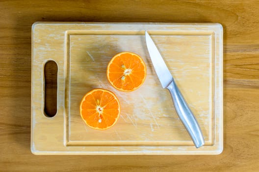 A sliced orange by knife on the wood block and on the wood table.