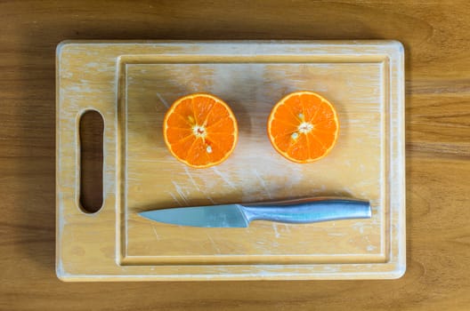 A sliced orange by knife on the wood block and on the wood table.