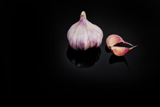 Garlic with reflection on black background.