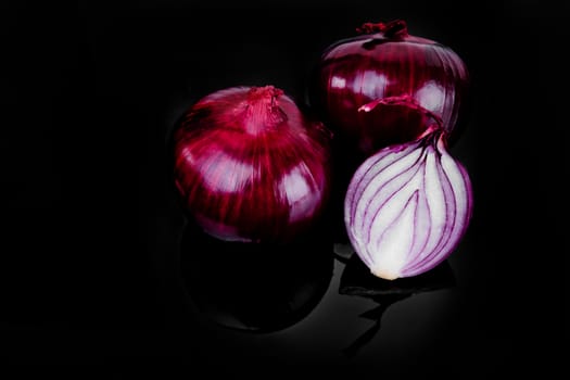 Red onion and half slice on black background with reflect.