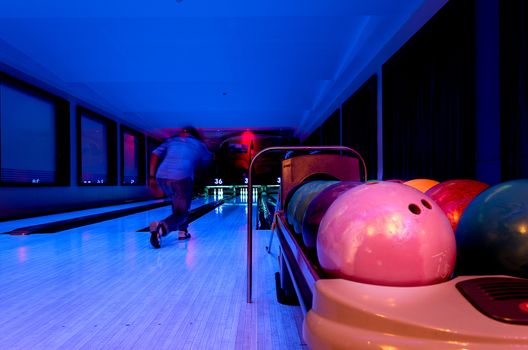 A Pink Bowling balls has ready for player to throwing ball on the wooden lane and in the bowling hall.